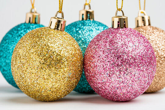Hanging glitter christmas baubles in gold pink and turquoise colors with christmas ornamen