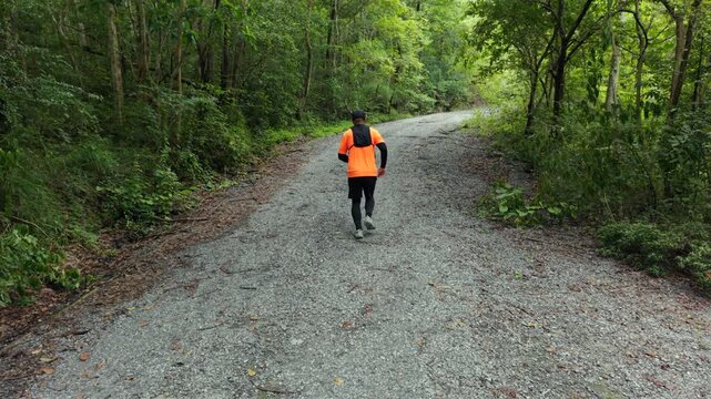 Drone view of man trail running through a mountain forest. Extreme outdoor sport represents endurance and personal challenge while pursuing fitness goals, achievement and a healthy active lifestyle.

