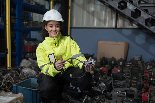 Woman worker working and inspecting components of electric motor or electronic equipment parts in warehouse