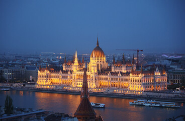 Naklejka premium Hungarian Parliament illuminated at blue hour across the Danube with misty background