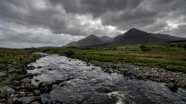 Dramatic perspective view of Shimna River in foreground with Mourne Mountains in background surrounded by fields under dramatic cloudscape representing Irish landscape beauty perspective view of a