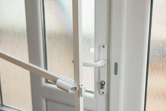 Plastic door handle detail close up, modern white pvc frame lock mechanism for home security concept