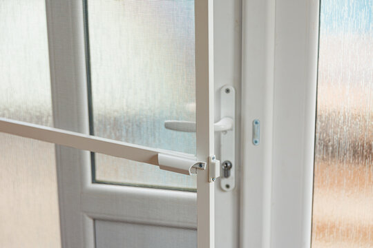 Plastic door handle detail close up, modern white pvc frame lock mechanism for home security concept
