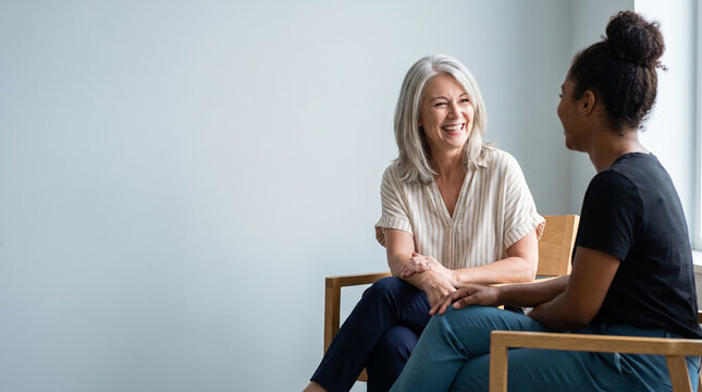 Cheerful Senior Woman Therapist Laughing During Counseling Session with Young Black Female Client, Happy Diverse People Having Friendly Conversation at Office with Copy Space