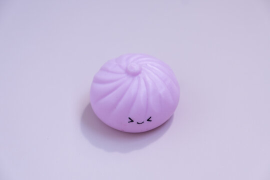 Small pink dumpling toy sits alone on a flat surface during daylight hours