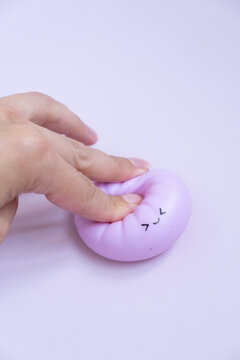 Person squeezes a soft dumpling toy with a smiley face in a bright room during daytime