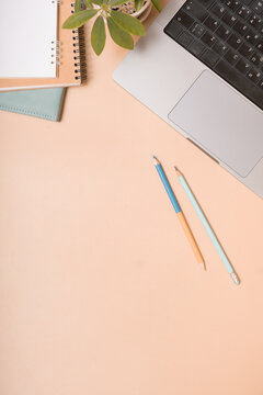 Workspace with laptop, notebooks, and colored pencils on a light background