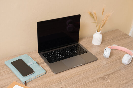 Workspace with laptop, notebook, smartphone and headphones on wooden desk