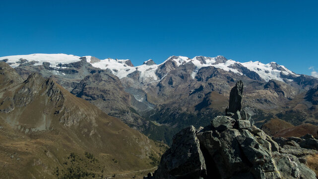 Stone cairn marker on Monte Facciabella peak with scenic view of Monte Rosa massif, Aosta Valley, Italy