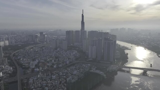 Aerial drone view of Landmark 81 in Thanh My Tay Ward, Ho Chi Minh City, Vietnam, with bright sunlight illuminating the iconic skyscraper and surrounding modern urban landscape.