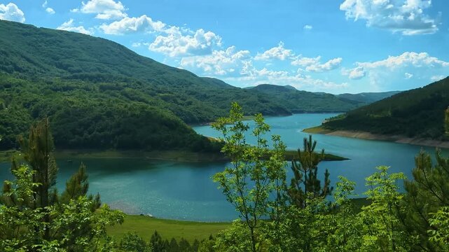 Lush green hills frame a tranquil lake. Zavoj Lake, Serbia