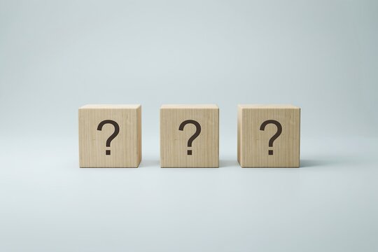 Three wooden blocks lined up in a row featuring black question marks against a light background