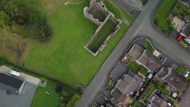 Top down aerial flying over village rooftops to the ruins of Castle Caulfield, County Tyrone, Northern Ireland