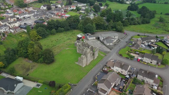 Aerial pull back from the ruins of Castle Caulfield to reveal Castlecaulfield village and the patchwork farmland of County Tyrone, Northern Ireland