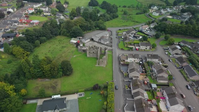 Aerial reveal of the Castle Caulfield ruins standing among village houses in Castlecaulfield, County Tyrone, Northern Ireland