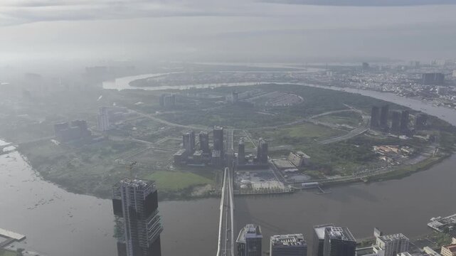Aerial drone view of Thu Thiem, Saigon River and Ba Son Bridge, with Bitexco Financial Tower in Ho Chi Minh City, Vietnam, illuminated by bright sunlight over the modern urban skyline.