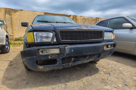 Damaged Blue Car Front View on Dirt Ground