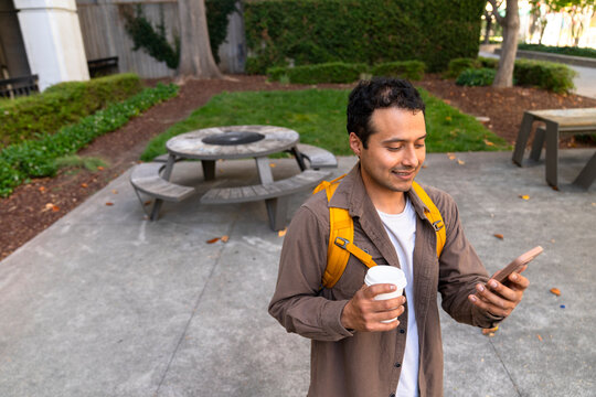 portrait of casual professional looking at mobile phone paper cup