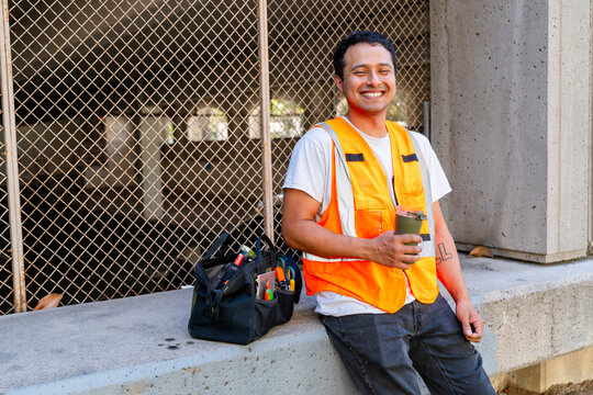 happy smiling construction worker in city drinking coffee break