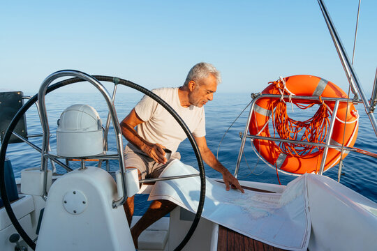 Senior man navigating sailing boat with map