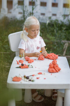 Child make models out of dough outdoors