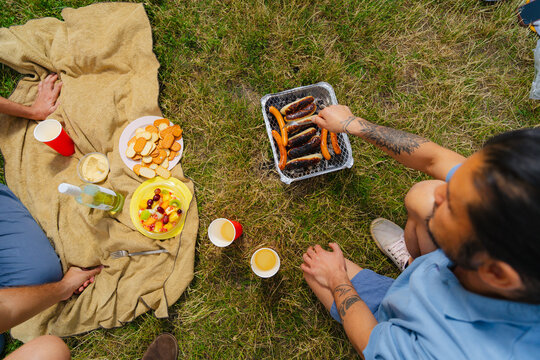 Friends Grilling Sausages at Picnic