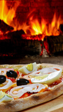 Authentic Portuguese-style pizza with boiled eggs, black olives, onions, and tomatoes, baked in a traditional wood-burning brick oven.