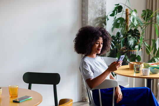 Relaxed Businesswoman Checking Phone During Breakfast at Cafeteria