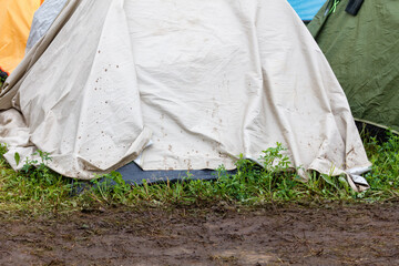 Tent covers muddy ground with grass nearby © schankz