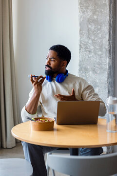 Man Working From Office Cafeteria With Laptop and Headphones