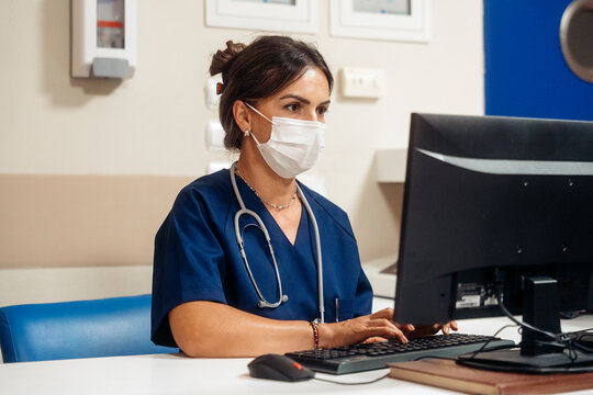 Doctor wearing face mask typing on computer