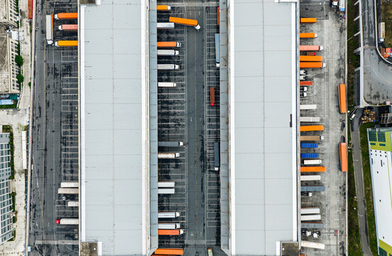Aerial top view of logistics warehouse with solar rooftops and trucks