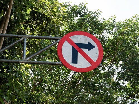 Circular red prohibition road sign with right arrow symbol regulating street traffic outdoors.
