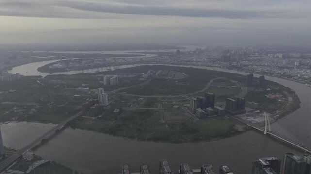 Aerial drone view of Thu Thiem, Saigon River and Ba Son Bridge, with Bitexco Financial Tower in Ho Chi Minh City, Vietnam, illuminated by bright sunlight over the modern urban skyline.