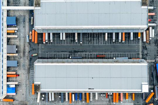 Aerial top view of logistics warehouse with solar rooftops and trucks