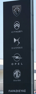 Greece, Rhodes, August 17. 2026, multi-brand outdoor signage pylon displaying the corporate logos of Peugeot, Citroen, DS Automobiles, Opel, and MG.