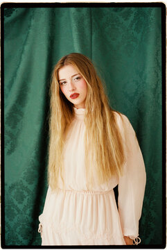 Woman against green damask curtain
