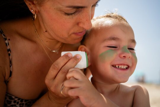 Mother applying sunscreen to son's face