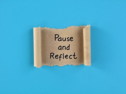 Pause and reflect text handwritten on a torn craft paper scroll over a blue background. Ideal concept for mindfulness, mental health, self-care, business evaluation, and personal growth