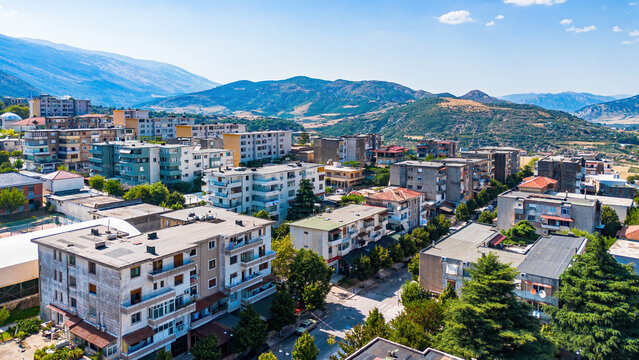 Aerial drone view of the urban cityscape, residential apartment buildings, and distant mountain ranges in Tepelene, Albania