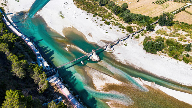 Aerial drone view of the historic Ali Pasha Bridge ruins spanning the wide, meandering Vjosa River bed in Tepelene, Albania