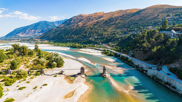 Aerial drone view of the historic Ali Pasha Bridge ruins spanning the wide, meandering Vjosa River bed in Tepelene, Albania