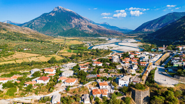 Aerial view of the rugged mountain landscape, Tepelene Castle ruins, and the wide riverbed of the Vjosa in Albania