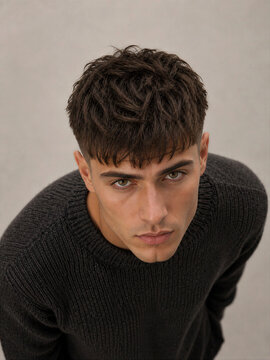 Young man with textured hair wearing a dark sweater looking up