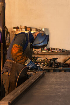 Side view of industrial welder preparing to weld metal pieces with torch