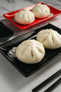 Steamed bao buns with chopped green onion served on black plate