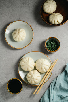 Top view of steamed bao buns with soy sauce and green onion
