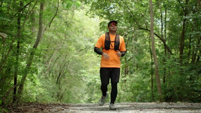Determined man trail running through a forest during an extreme outdoor workout. He pushes his limits while pursuing fitness goals, endurance personal achievement through an active healthy lifestyle.
