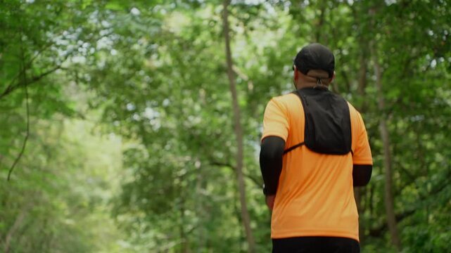 Determined man trail running through a forest during an extreme outdoor workout. He pushes his limits while pursuing fitness goals, endurance personal achievement through an active healthy lifestyle.
