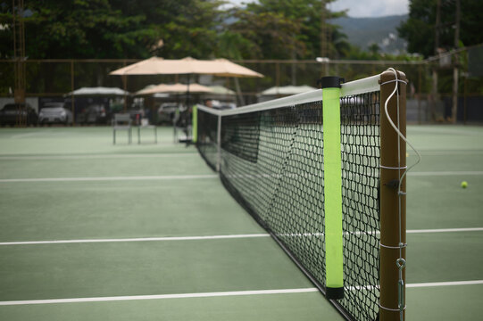Tennis Court Net Close Up with Green Hard Court Surface and Blurred Background Outdoors